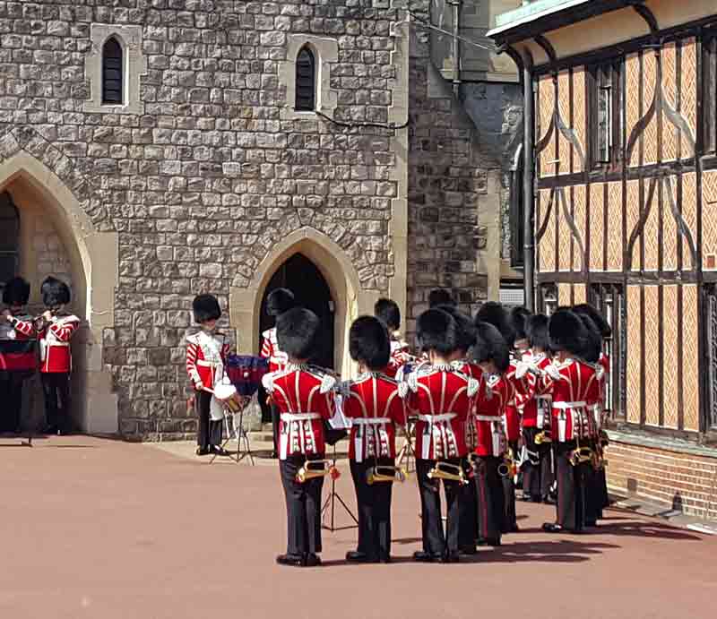 Inparade ground wearing red uniform and busby hats.